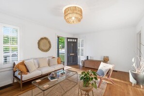 A modern living room with a sofa, coffee table, and a door leading outside.