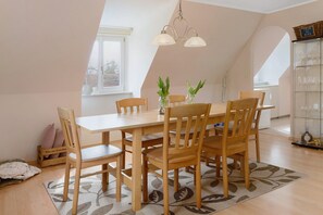 Un coin repas avec une table et des chaises en bois, un lustre et une vitrine contenant divers objets.