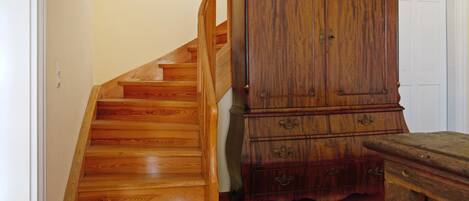Una escalera de madera que conduce a una plataforma con un armario y una puerta al fondo.