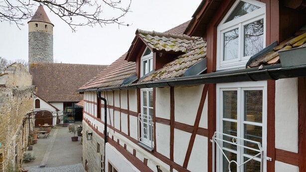 A narrow cobblestone street flanked by traditional half-timbered houses with a tower in the background. - Apartment 'Schwanbergblick' with Shared Garden and Wi-Fi (Iphofen)