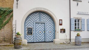A building with a large arched entrance, a sign above the door, and two barrels on the ground. - Apartment 'Schwanbergblick' with Shared Garden and Wi-Fi (Iphofen)