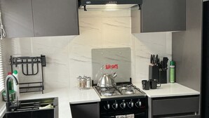 A modern kitchen with a black stove, white countertops, and dark cabinets. - Cosy modern cottage only 10 minutes from the city centre (Mutare)