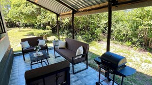 Un patio al aire libre con zona techada, mobiliario y una parrilla para barbacoa.