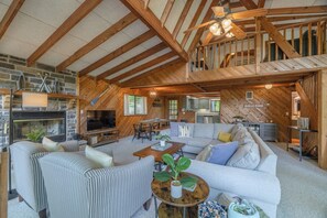 A spacious living area with a stone fireplace, a television, and a dining area. - Sycamore Shores by Innsbrook Vacations! (Innsbrook)