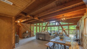 Un intérieur en bois comprenant un coin repas, un canapé et de grandes fenêtres.
