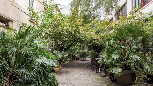 A cobblestone courtyard with potted plants and bicycles. - Merveil Family Suite - Fbg St Antoine (Paris)