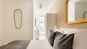 A bedroom with a bed, a mirror, and a view of a balcony. - Merveil Family Suite - Fbg St Antoine (Paris)
