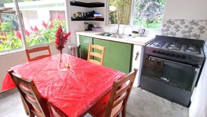 A compact kitchen with a gas stove, a sink, and a dining table with chairs. - Riverfront Home Perfect for Groups in the Middle of the Mountains (Vallejito Abajo)