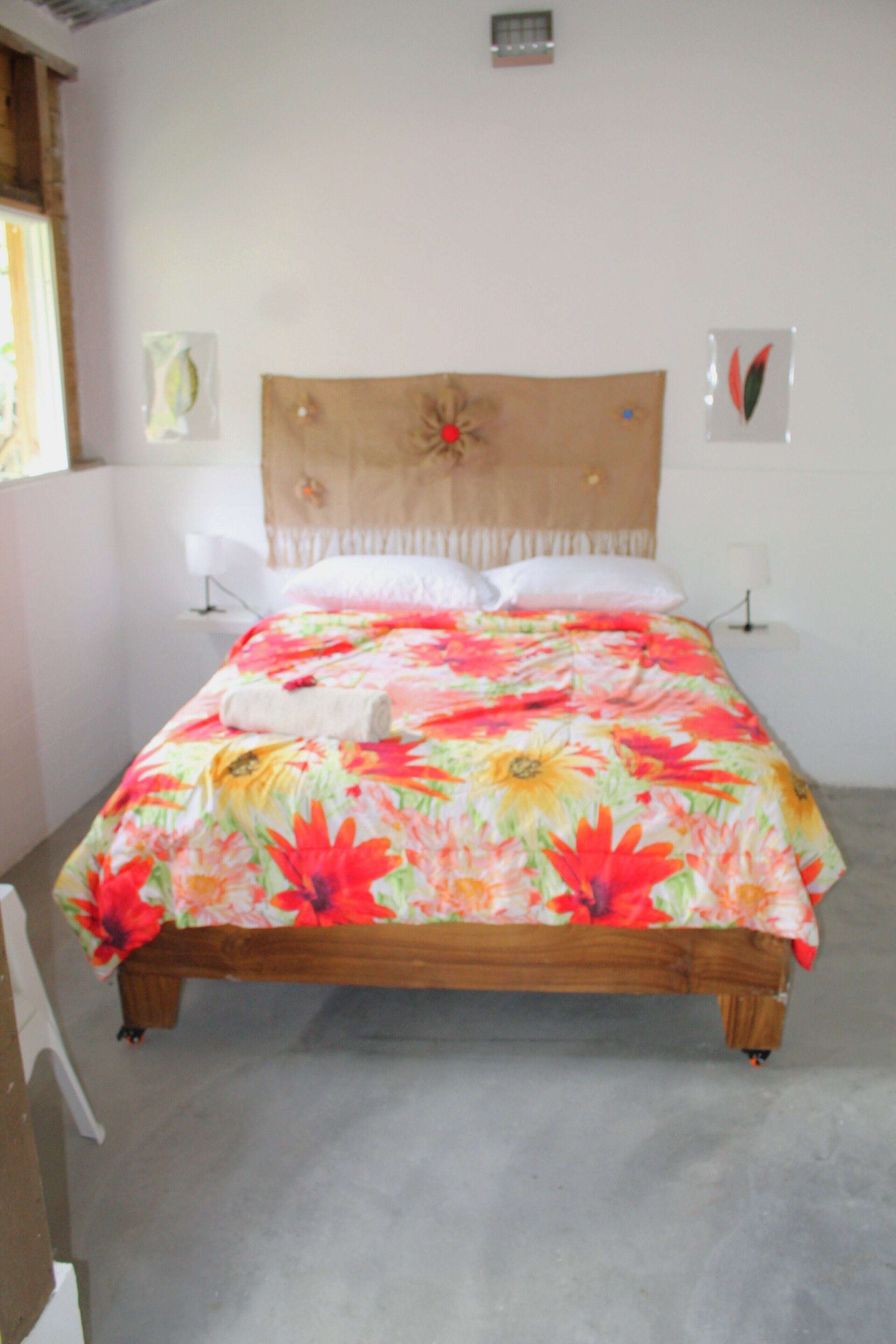 Ein Bett mit floralem Überwurf, einem Holz-Kopfteil und zwei Nachttischlampen.