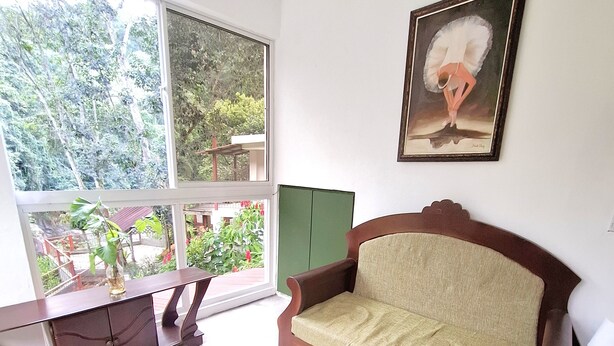 A room with a large window, a wooden sofa, a green cabinet, and a painting on the wall. - Riverfront Home Perfect for Groups in the Middle of the Mountains (Vallejito Abajo)