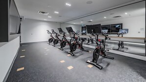 A modern gym with stationary bikes, mirrors, and exercise equipment. - High Rise 1BR Condo w Balcony Beautiful Views (Kitchener)