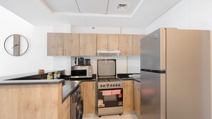 Een moderne keuken met houten kastjes, een roestvrijstalen koelkast, een magnetron, een fornuis en een vaatwasser.