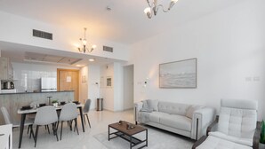 Een moderne woonkamer met een bank, fauteuil, salontafel en een eetgedeelte met stoelen en een tafel.
