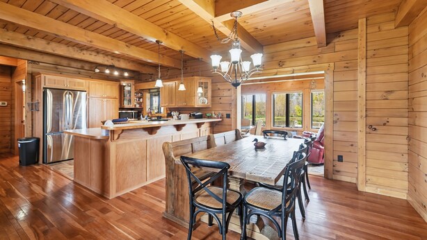 Una cabaña de madera espaciosa con una gran mesa de comedor, armarios de madera y una cocina moderna.