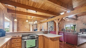 Una cocina amplia con vigas de madera, una isla grande y un sofá de cuero rojo en la zona de estar.