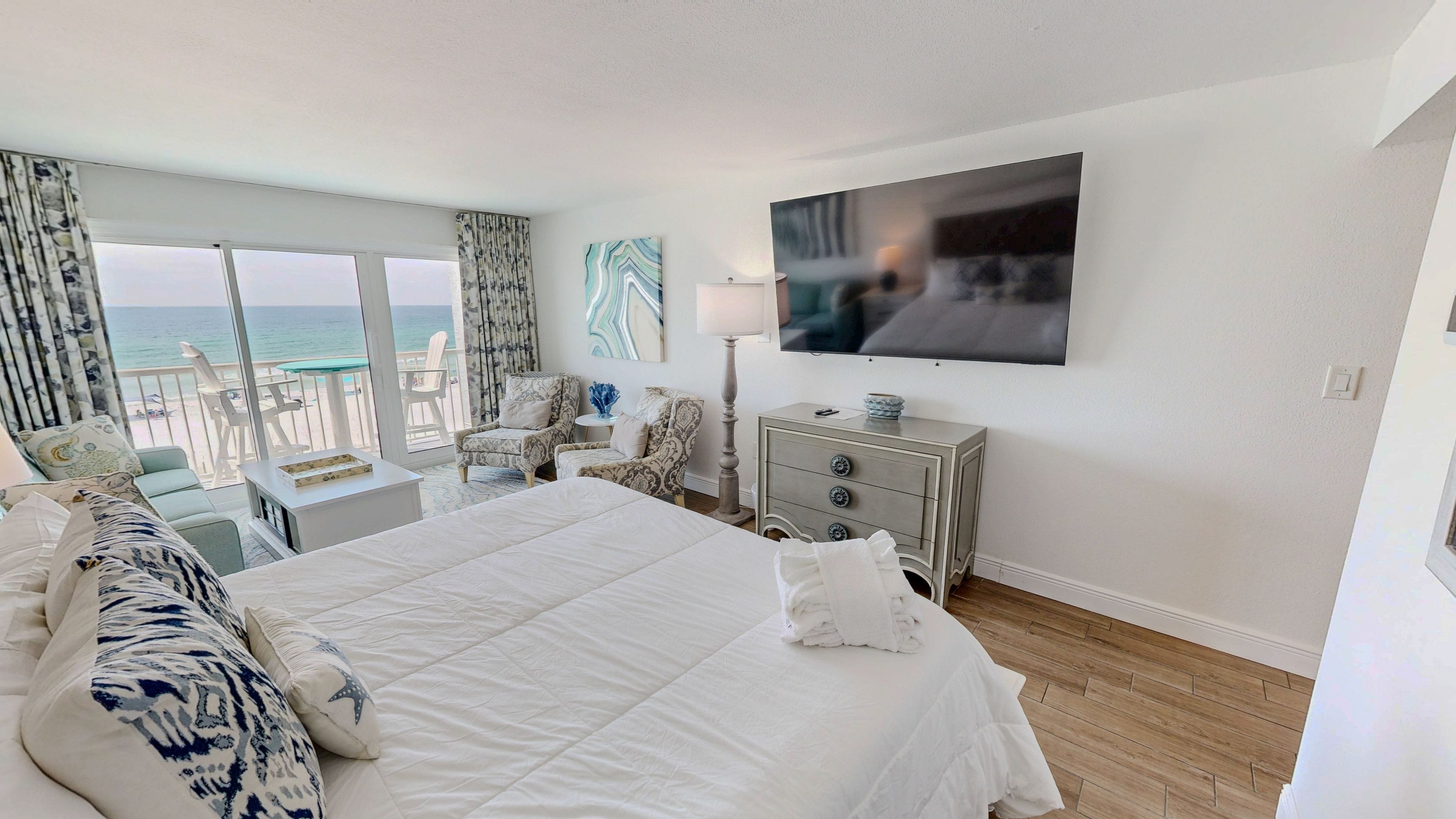 Una camera d'albergo con un letto grande, una televisione, una scrivania e vista sull'oceano.