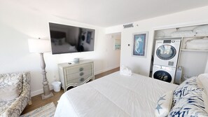 A bedroom with a bed, dresser, television, and a washing machine. - Islander Beach Resort 403 Condo (Fort Walton Beach)