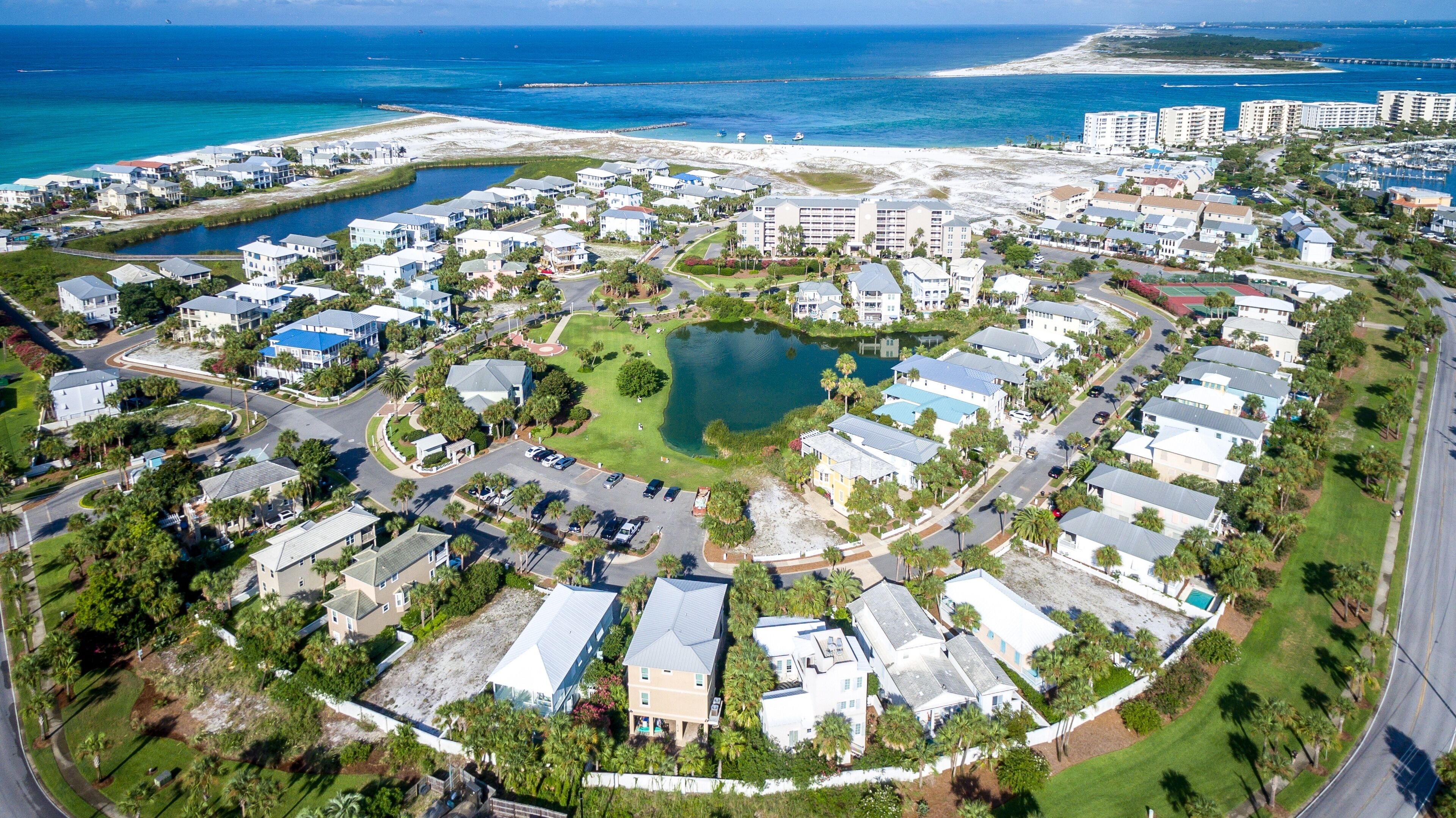 An aerial view of a coastal residential area with a central lake, surrounded by single-family homes and a marina.
