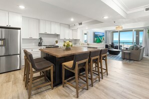 Una cocina moderna con armarios blancos, un refrigerador de acero inoxidable y una isla de madera con taburetes de bar.