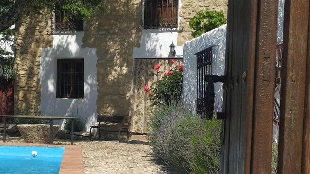 Une cour dallée de pierres, avec une piscine, un banc et un bâtiment doté d’un balcon.