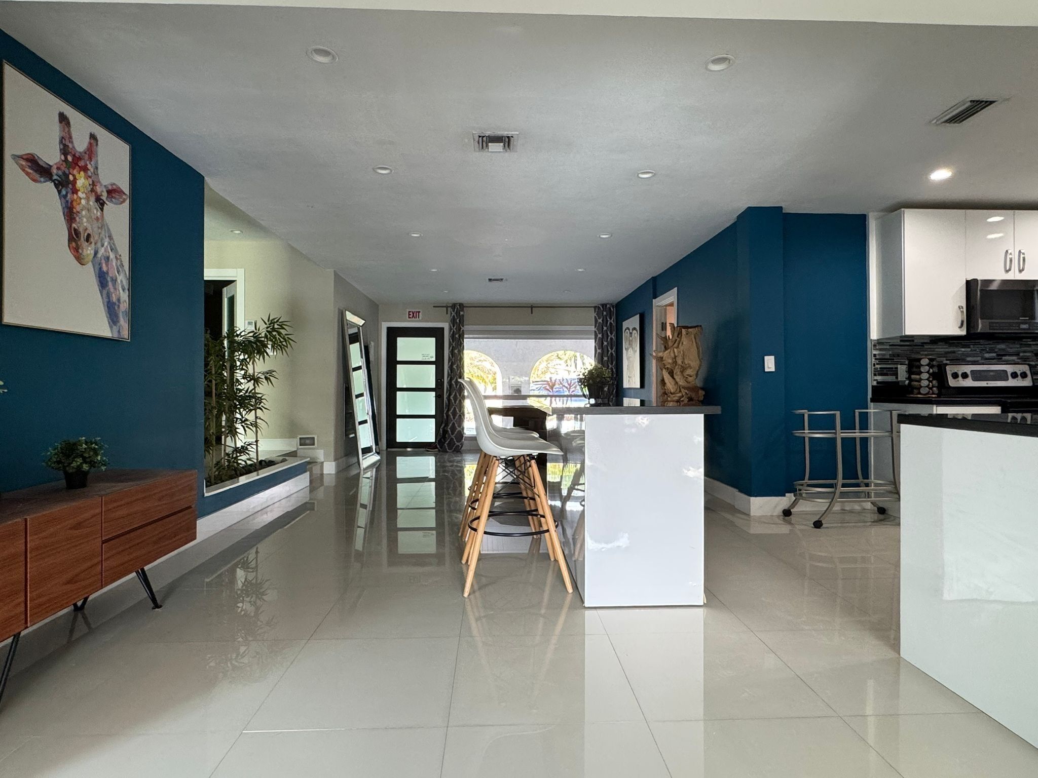 A modern kitchen with white cabinets, a black microwave, and a stainless steel range hood.
