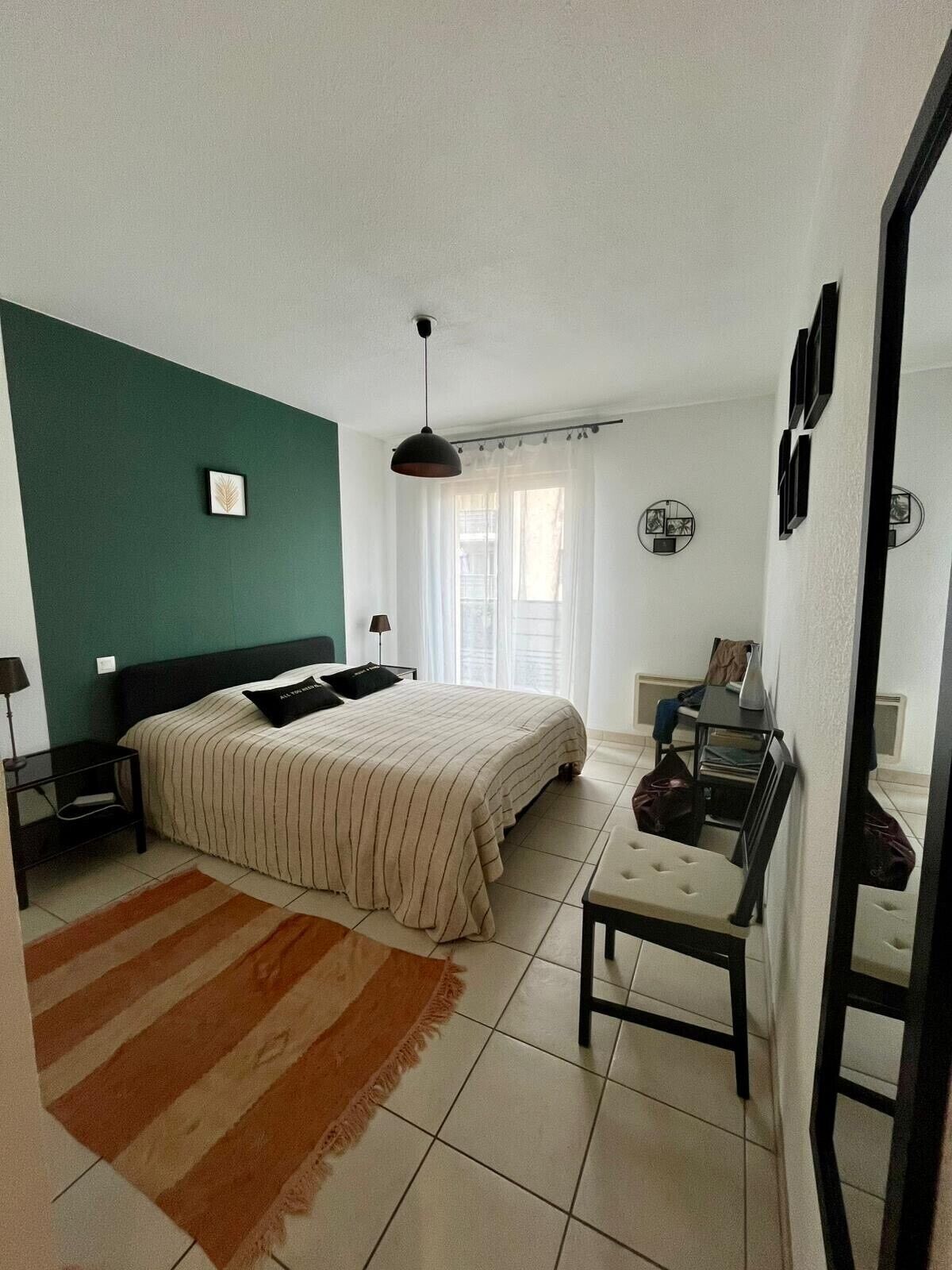 A bedroom with a bed, nightstands, a desk, and a chair.