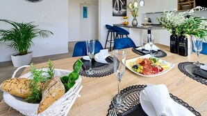 A dining area with a round table set for two, featuring a basket of bread, a plate of fruit, and a glass of water. - 2-Bedroom Holiday Villa Noa (Orebić)