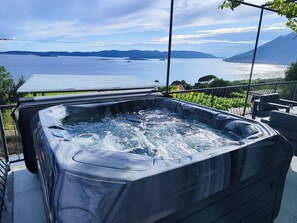 A hot tub with a view of a lake and mountains.