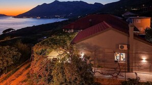 A coastal property with a red-roofed building, a paved driveway, and a view of the sea and mountains. - 2-Bedroom Holiday Villa Noa (Orebić)