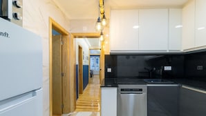 A modern kitchen with a dishwasher, a stove, and wooden flooring.