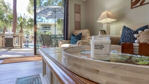 Una habitación con vista a una piscina y área exterior, una lámpara, un tarro etiquetado como “Smells Like Hilton Head Island, SC” y un libro sobre la mesa.