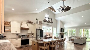 Une cuisine spacieuse avec un grand îlot central, des armoires en bois et une enseigne de style rustique.