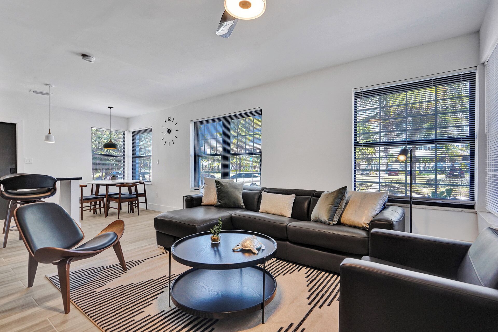 A modern living room with a sectional sofa, a round coffee table, and a dining area with a table and chairs.