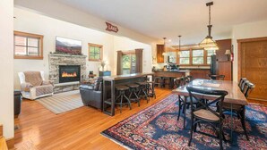A spacious living area with a fireplace, a bar, and a dining table with chairs.