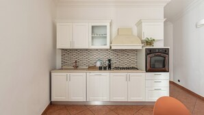 A compact kitchen with white cabinets, a tiled backsplash, a gas stove, and a built-in oven. - Gorizia Apartment by Wonderful Italy (Palermo)