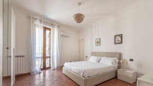 A bedroom with a bed, nightstand, and a window with curtains. - Gorizia Apartment by Wonderful Italy (Palermo)