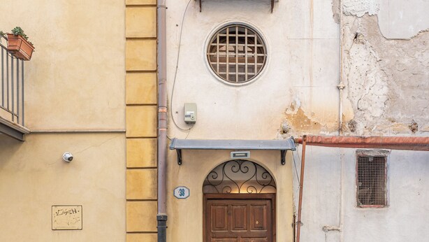 A building with a wooden door, a small window with a metal grille, and a number '30' sign on the wall. - Gorizia Apartment by Wonderful Italy (Palermo)