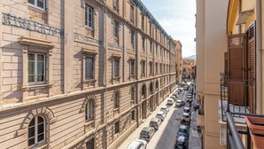A street view of a historic building with multiple windows and balconies, lined with parked cars. - Gorizia Apartment by Wonderful Italy (Palermo)