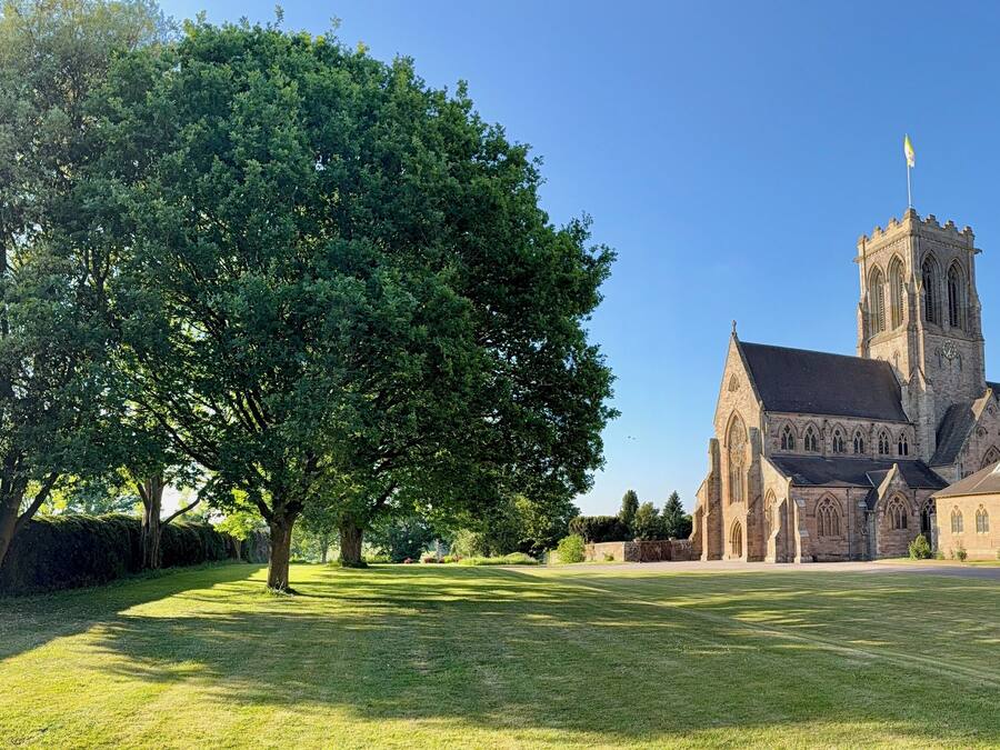 Eine große Kirche mit einem markanten Turm und einem gepflegten Rasen davor.