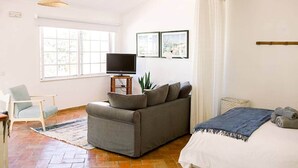 Une pièce avec un canapé, un lit, une télévision et une fenêtre.