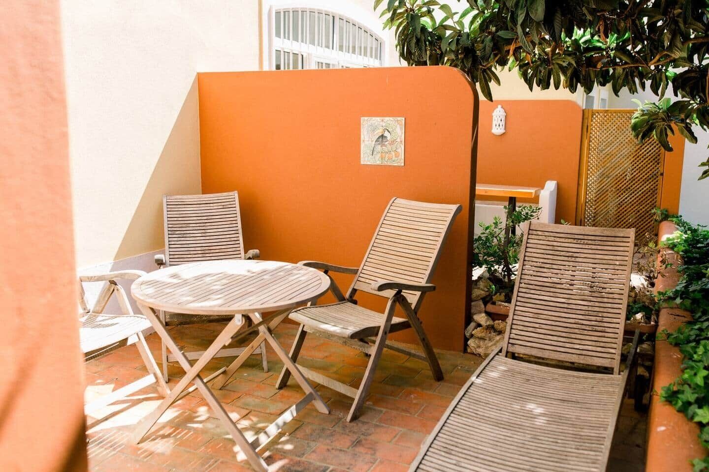 A patio with a round table and two chairs, a small plant, and a decorative wall.