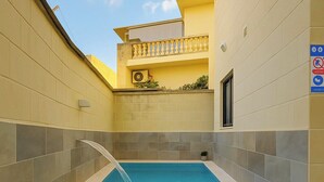 Une piscine avec une terrasse carrelée, un petit balcon agrémenté de plantes et un panneau indiquant qu’il est interdit de fumer.