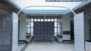 A building entrance with a large metal gate, a covered walkway, and potted plants on either side. - Nakuru Guest Suites (Nakuru)