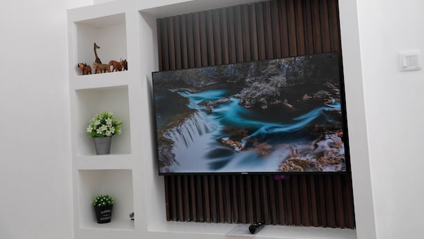 A flat-screen TV mounted on a wall with wooden paneling above it. - Nakuru Guest Suites (Nakuru)