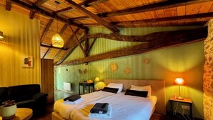 Ein gemütliches Zimmer mit einem großen Bett, einem kleinen Schreibtisch, einem Stuhl und einer Lampe.