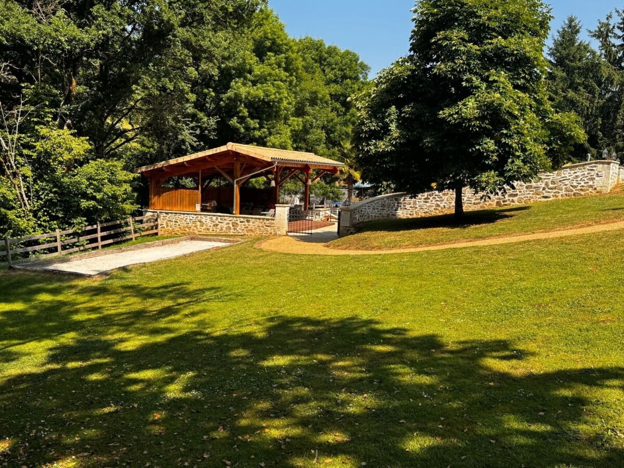 En park med et træpavillon, stenvægge og en græsplæne.