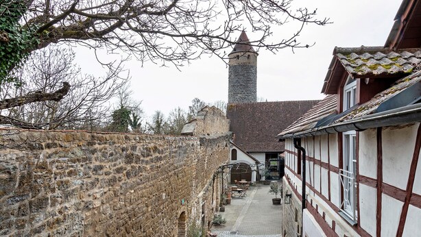 A narrow street with stone walls, a tower, and traditional half-timbered buildings. - Apartment 'Eulenturm' with Shared Garden, Balcony and Wi-Fi (Iphofen)