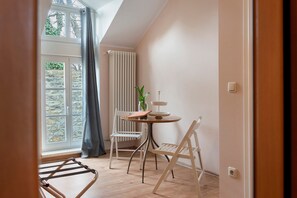 A room with a table, chairs, a radiator, and a window with curtains.