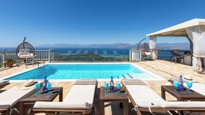 A poolside area with lounge chairs, a hanging chair, and a table with drinks. - Orizzonte Blu - Three Bedroom Villa, Sleeps 6 (Corfu)