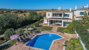 Una casa de dos pisos con piscina, mobiliario exterior y vistas al campo.
